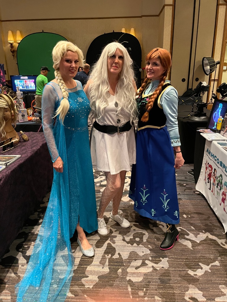 Three women cosplaying as Elsa, Ana, and Olaf
